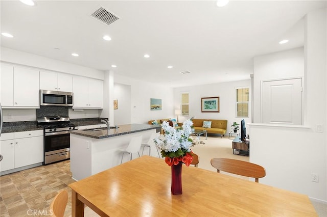 31268 Via Nubes, Temecula, CA 92592 - kitchen featuring appliances with stainless steel finishes, white cabinetry, recessed lighting, a center island with sink, and a kitchen breakfast bar