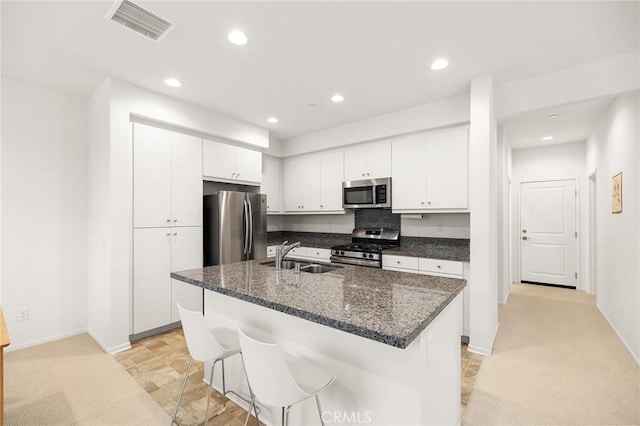31268 Via Nubes, Temecula, CA 92592 - kitchen with stainless steel appliances, white cabinetry, a breakfast bar, a kitchen island with sink, and recessed lighting