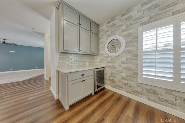 25904 Bear Valley Rd, Tehachapi, CA 93561 - indoor dry bar featuring beverage cooler, wallpapered walls, an accent wall, a ceiling fan, and dark wood finished floors