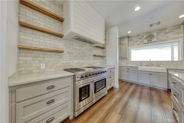 25904 Bear Valley Rd, Tehachapi, CA 93561 - kitchen featuring open shelves, double oven range, tasteful backsplash, premium range hood, and wood finished floors