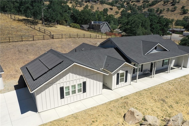 25904 Bear Valley Rd, Tehachapi, CA 93561 - back of house with board and batten siding, roof mounted solar panels, a patio, and roof with shingles