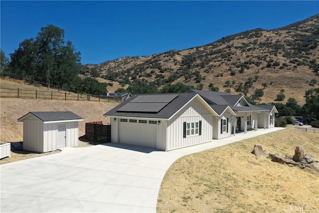 25904 Bear Valley Rd, Tehachapi, CA 93561 - modern farmhouse featuring board and batten siding, concrete driveway, a storage unit, solar panels, and a garage