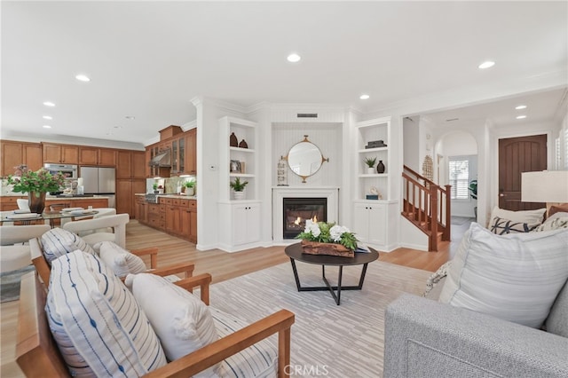 26 Los Indios, Irvine, CA 92618 - living room with light wood-style floors, arched walkways, stairs, a glass covered fireplace, and recessed lighting