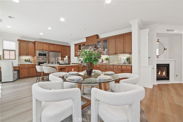 26 Los Indios, Irvine, CA 92618 - dining area with ornamental molding, light wood-style floors, a glass covered fireplace, and recessed lighting