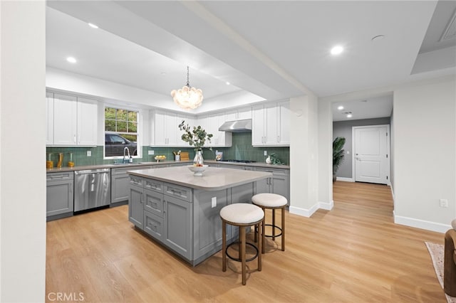 600 Baldwin Ct, Sierra Madre, CA 91024 - kitchen featuring stainless steel dishwasher, gray cabinetry, under cabinet range hood, a tray ceiling, and a kitchen bar