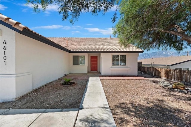 66101 14th St, Desert Hot Springs, CA 92240 - view of exterior entry with stucco siding, a tiled roof, and a patio