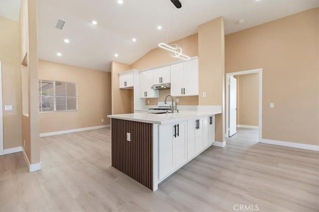 66101 14th St, Desert Hot Springs, CA 92240 - kitchen with light countertops, white cabinets, under cabinet range hood, lofted ceiling, and light wood-type flooring