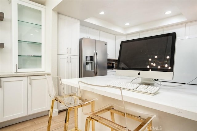16521 Grunion Ln Unit 207, Huntington Beach, CA 92649 - kitchen featuring appliances with stainless steel finishes, white cabinetry, a raised ceiling, light stone counters, and recessed lighting