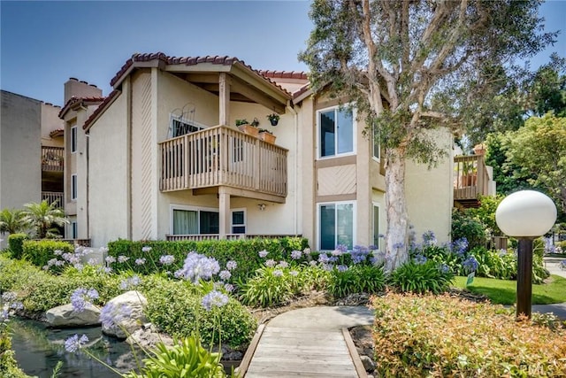 16521 Grunion Ln Unit 207, Huntington Beach, CA 92649 - back of house with stucco siding, a tiled roof, and a balcony