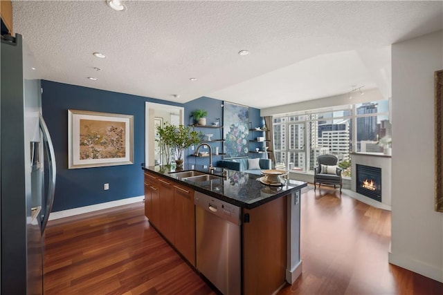 1199 Pacific Unit 1303, San Diego, CA 92101 - kitchen featuring appliances with stainless steel finishes, dark wood-style floors, a center island with sink, a textured ceiling, and open floor plan