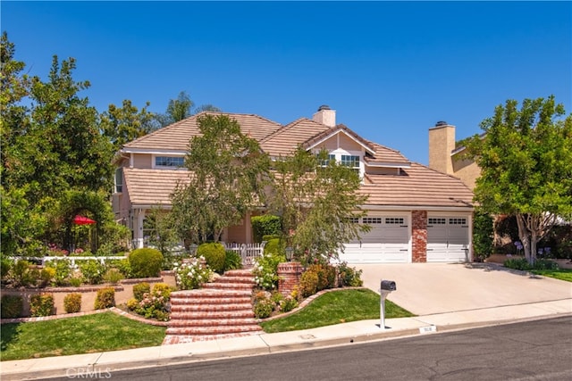 968 Saddlehorn Pl, Newbury Park, CA 91320 - view of property hidden behind natural elements featuring driveway, a chimney, a garage, a tile roof, and stairway
