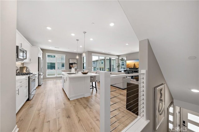 2890 Via Alta Pl, San Diego, CA 92108 - kitchen with stainless steel appliances, recessed lighting, open floor plan, white cabinets, and a kitchen bar