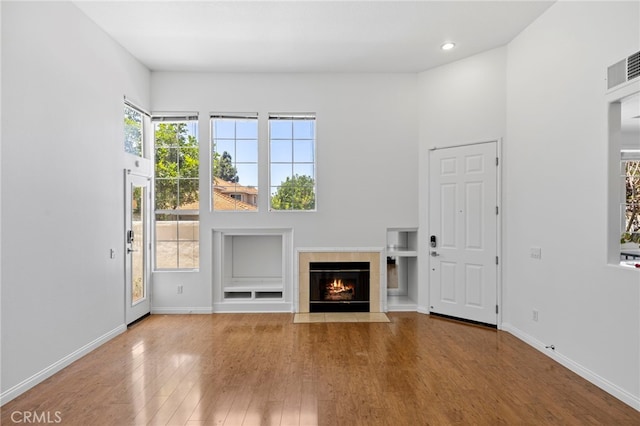 27884 Via De Costa, San Juan Capistrano, CA 92675 - unfurnished living room with wood finished floors, a tiled fireplace, recessed lighting, and a towering ceiling