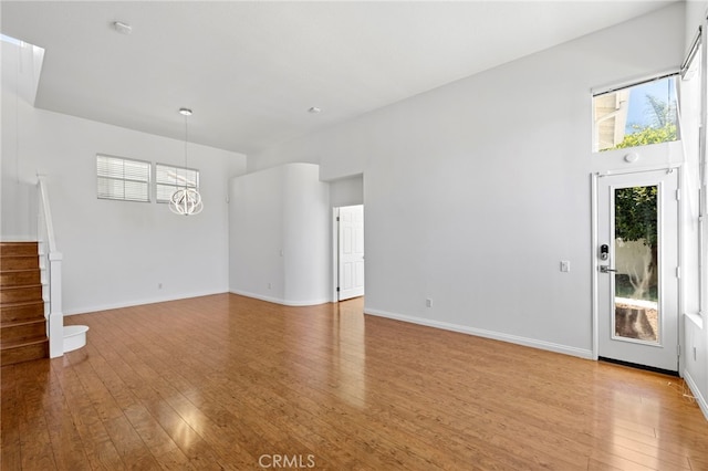 27884 Via De Costa, San Juan Capistrano, CA 92675 - unfurnished living room with light wood-style floors, a chandelier, and stairway