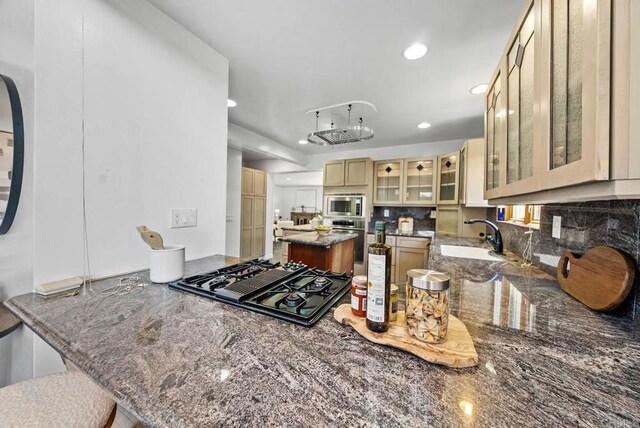 7439 Carrie Ridge Way, San Diego, CA 92139 - kitchen with stainless steel appliances, backsplash, dark stone countertops, a peninsula, and glass insert cabinets