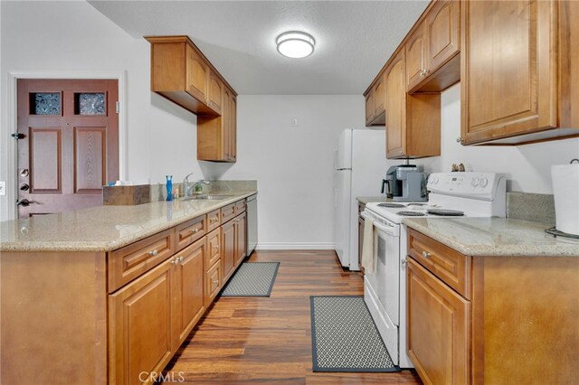 2500 San Gabriel Way Unit 306, Corona, CA 92882 - kitchen with white appliances, dark wood-type flooring, light stone counters, a peninsula, and brown cabinetry