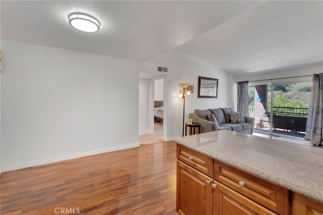 2500 San Gabriel Way Unit 306, Corona, CA 92882 - kitchen with wood finished floors, open floor plan, brown cabinetry, and vaulted ceiling
