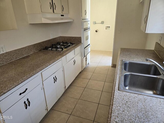 45409 Rodin Ave, Lancaster, CA 93535 - kitchen with stainless steel gas cooktop, under cabinet range hood, a warming drawer, white cabinets, and light tile patterned floors