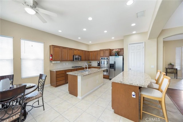 60284 Honeysuckle St, La Quinta, CA 92253 - kitchen featuring appliances with stainless steel finishes, a kitchen island with sink, recessed lighting, light stone counters, and tasteful backsplash