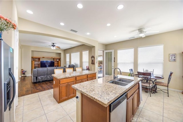 60284 Honeysuckle St, La Quinta, CA 92253 - kitchen featuring ceiling fan, appliances with stainless steel finishes, an island with sink, brown cabinetry, and light tile patterned floors
