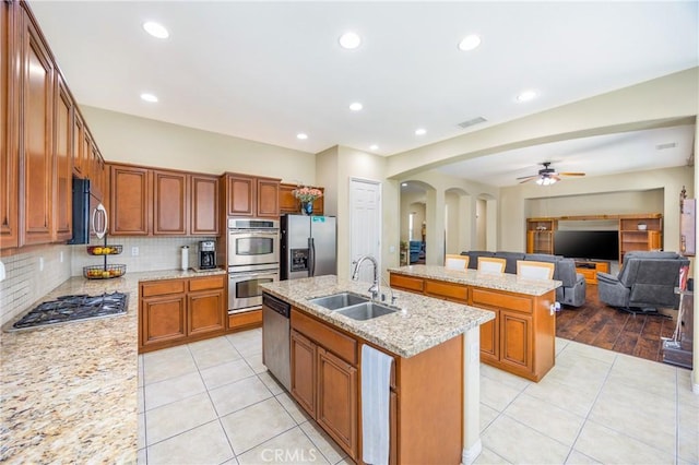 60284 Honeysuckle St, La Quinta, CA 92253 - kitchen with stainless steel appliances, a kitchen island with sink, arched walkways, light tile patterned floors, and recessed lighting