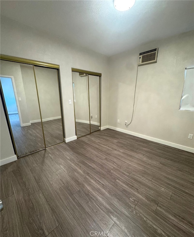 7892 8th St, Buena Park, CA 90621 - unfurnished bedroom with multiple closets, dark wood-style flooring, and an AC wall unit