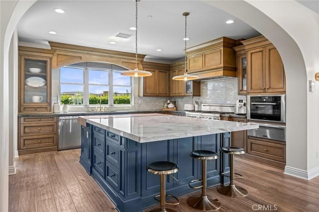 3 Stockmen Rd, Ladera Ranch, CA 92694 - kitchen featuring a warming drawer, stainless steel appliances, brown cabinets, a kitchen island, and hardwood / wood-style flooring