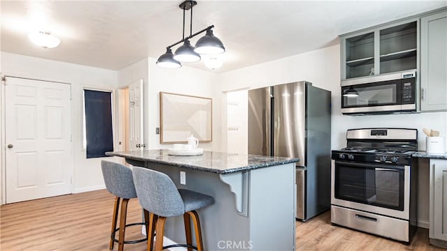 29282 Pine Dr, Cedar Glen, CA 92321 - kitchen featuring appliances with stainless steel finishes, a kitchen island, light wood-style floors, a kitchen bar, and dark stone countertops