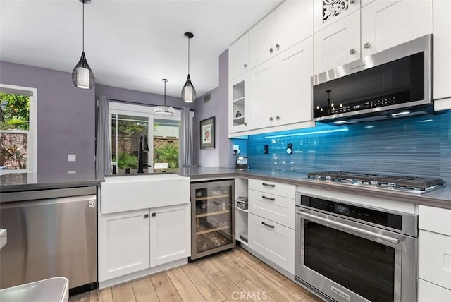 15 Surfbird Ln, Aliso Viejo, CA 92656 - kitchen with stainless steel appliances, wine cooler, light wood-type flooring, white cabinets, and hanging light fixtures