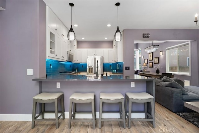 15 Surfbird Ln, Aliso Viejo, CA 92656 - kitchen featuring appliances with stainless steel finishes, light wood-style flooring, a peninsula, white cabinetry, and a kitchen bar