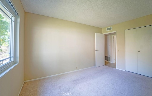 24612 Artemia Ave, Mission Viejo, CA 92691 - unfurnished bedroom with carpet, multiple windows, a textured ceiling, and a closet