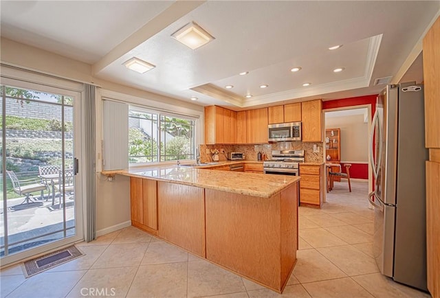 24612 Artemia Ave, Mission Viejo, CA 92691 - kitchen featuring appliances with stainless steel finishes, a peninsula, a tray ceiling, decorative backsplash, and light stone countertops
