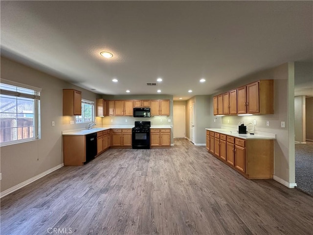 53024 Astrid Way, Lake Elsinore, CA 92532 - kitchen with black appliances, wood finished floors, recessed lighting, light countertops, and brown cabinets