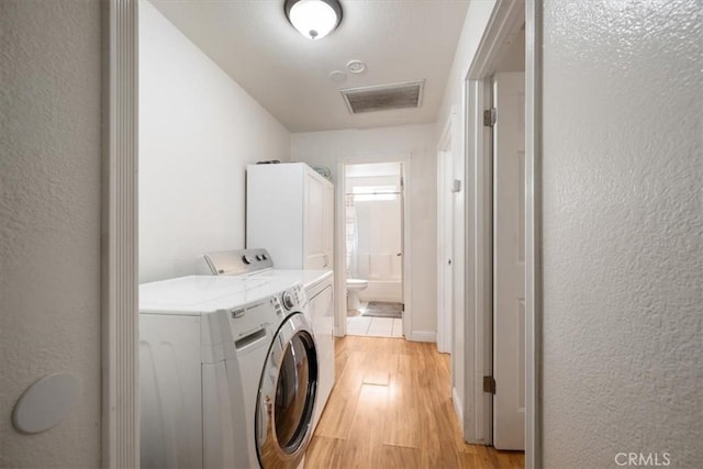 1812 Riverside Ave, Paso Robles, CA 93446 - washroom featuring light wood-type flooring, a textured wall, and separate washer and dryer