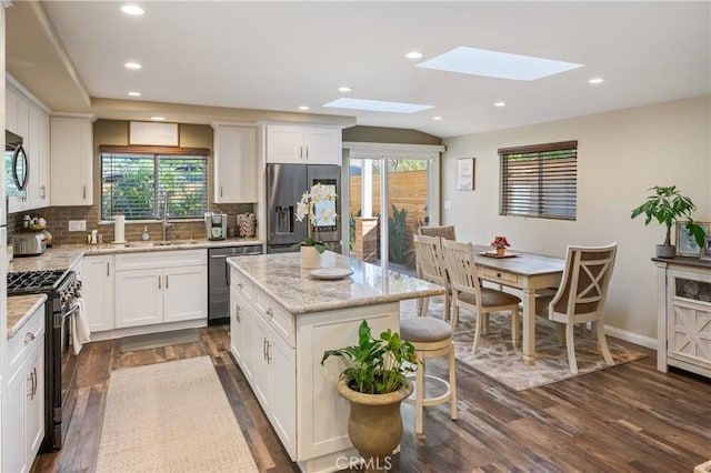 20092 E Frank Ln, Orange, CA 92869 - kitchen with appliances with stainless steel finishes, a skylight, dark wood finished floors, backsplash, and light stone counters