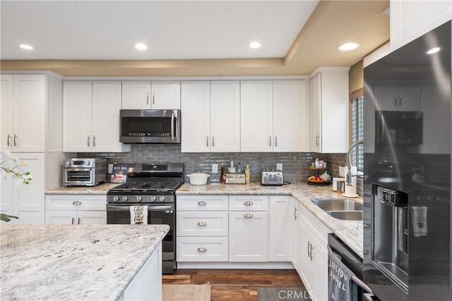 20092 E Frank Ln, Orange, CA 92869 - kitchen with stainless steel appliances, white cabinetry, tasteful backsplash, dark wood-style floors, and light stone counters