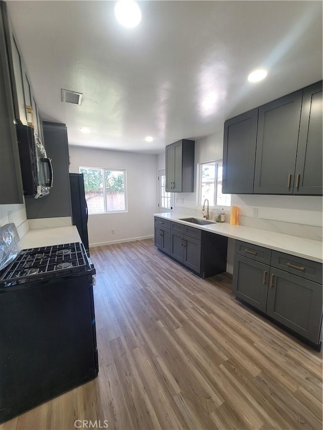 8339 Manzanar Ave, Pico Rivera, CA 90660 - kitchen with gas range oven, black refrigerator, wood finished floors, light countertops, and recessed lighting