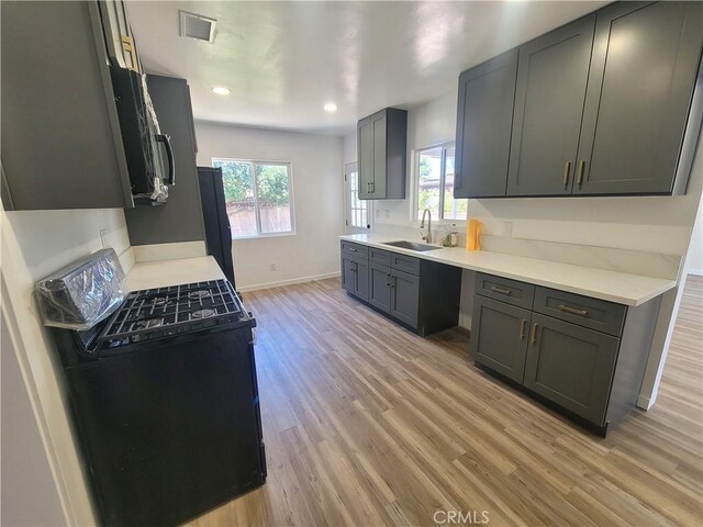 8339 Manzanar Ave, Pico Rivera, CA 90660 - kitchen with light wood-style floors, gas range, stainless steel microwave, light countertops, and recessed lighting