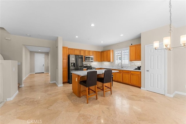 1581 Margit St, Redlands, CA 92374 - kitchen with appliances with stainless steel finishes, a center island, a chandelier, light countertops, and a kitchen bar