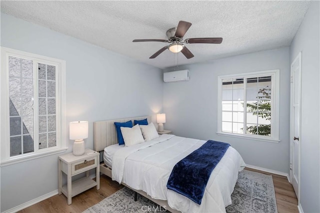 12108 Dunrobin Ave, Downey, CA 90242 - bedroom with wood finished floors, a textured ceiling, a wall mounted AC, and a ceiling fan