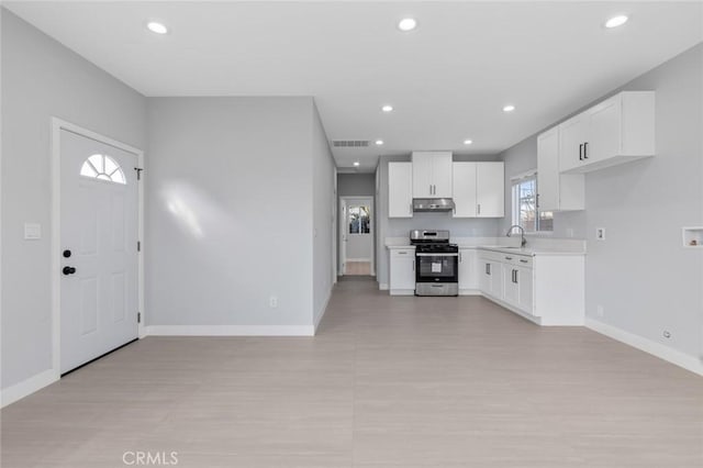 12108 Dunrobin Ave, Downey, CA 90242 - kitchen featuring gas range, under cabinet range hood, light countertops, white cabinets, and recessed lighting