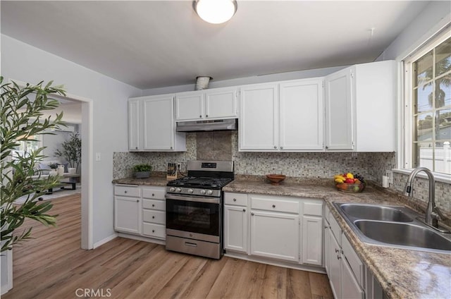 12108 Dunrobin Ave, Downey, CA 90242 - kitchen featuring stainless steel gas range oven, under cabinet range hood, light wood-style floors, tasteful backsplash, and white cabinetry