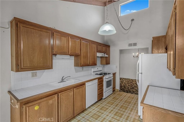 19950 Esquiline Ave, Walnut, CA 91789 - kitchen with white appliances, tile countertops, a towering ceiling, brown cabinets, and under cabinet range hood