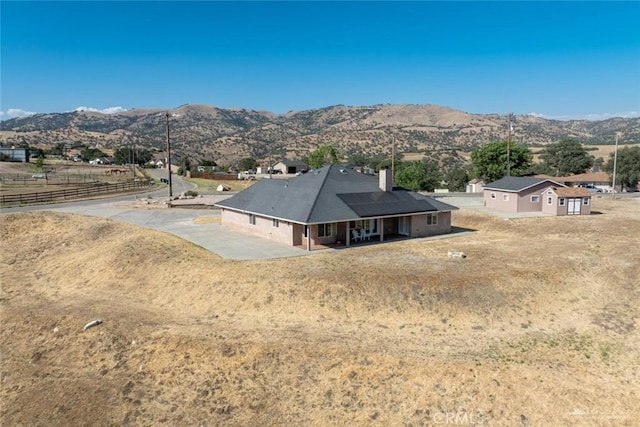23309 Tak Ct, Tehachapi, CA 93561 - back of property featuring a mountain view, a chimney, a patio area, and solar panels