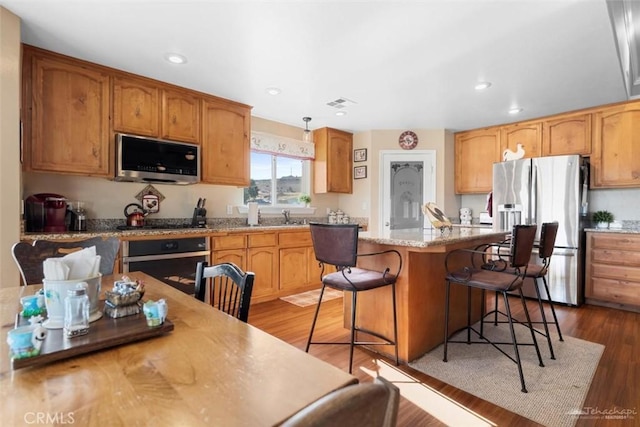 23309 Tak Ct, Tehachapi, CA 93561 - kitchen featuring appliances with stainless steel finishes, a kitchen bar, a center island, light countertops, and dark wood-type flooring