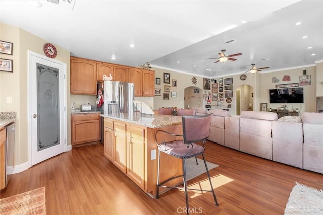 23309 Tak Ct, Tehachapi, CA 93561 - kitchen with arched walkways, ceiling fan, recessed lighting, a breakfast bar area, and light wood-style floors