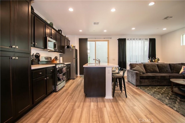 29392 Tourmaline Way, Winchester, CA 92596 - kitchen featuring appliances with stainless steel finishes, a breakfast bar, light wood-style floors, light countertops, and open floor plan