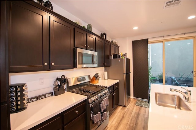 29392 Tourmaline Way, Winchester, CA 92596 - kitchen with appliances with stainless steel finishes, light wood-style floors, light countertops, dark brown cabinets, and recessed lighting