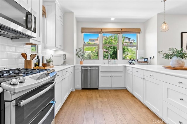 38 Marisol St, Rancho Mission Viejo, CA 92694 - kitchen with stainless steel appliances, light countertops, white cabinets, light wood-style floors, and decorative light fixtures