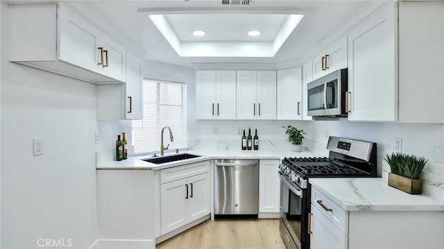 8810 Hewitt Pl Unit 2, Garden Grove, CA 92844 - kitchen with appliances with stainless steel finishes, a tray ceiling, white cabinetry, light wood finished floors, and light stone countertops